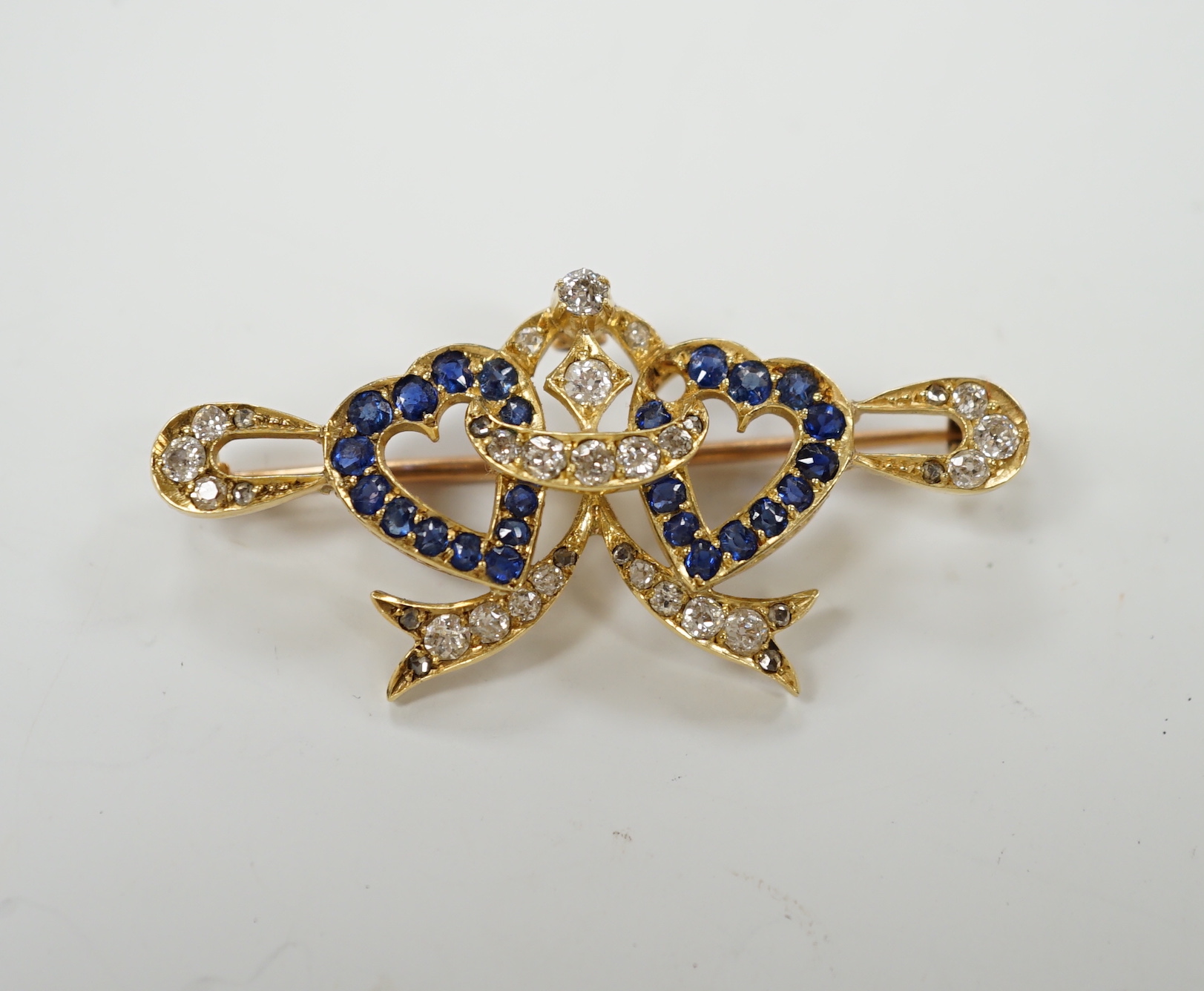 A yellow metal, sapphire and diamond set twin hearts bar brooch, 41mm, gross weight 4.8 grams.